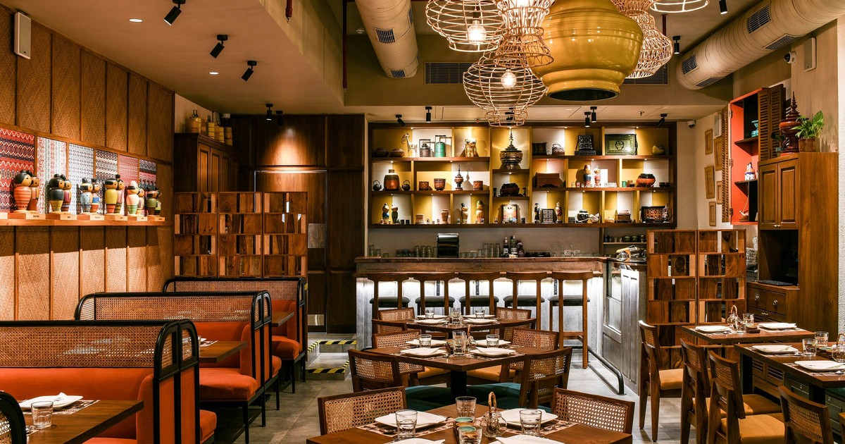 Restaurant met verschillende lichtlagen bij tafels, bar en plafond