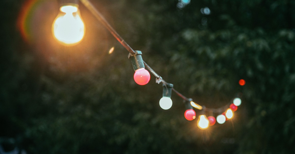 Gekleurde lampen aan een lichtsnoer in de tuin